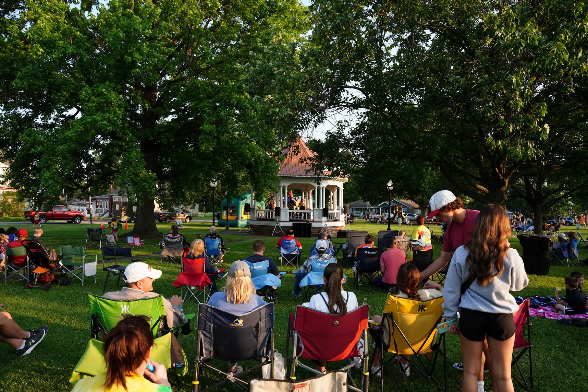 Crowd in the grass in camping chairs around a park pavillion